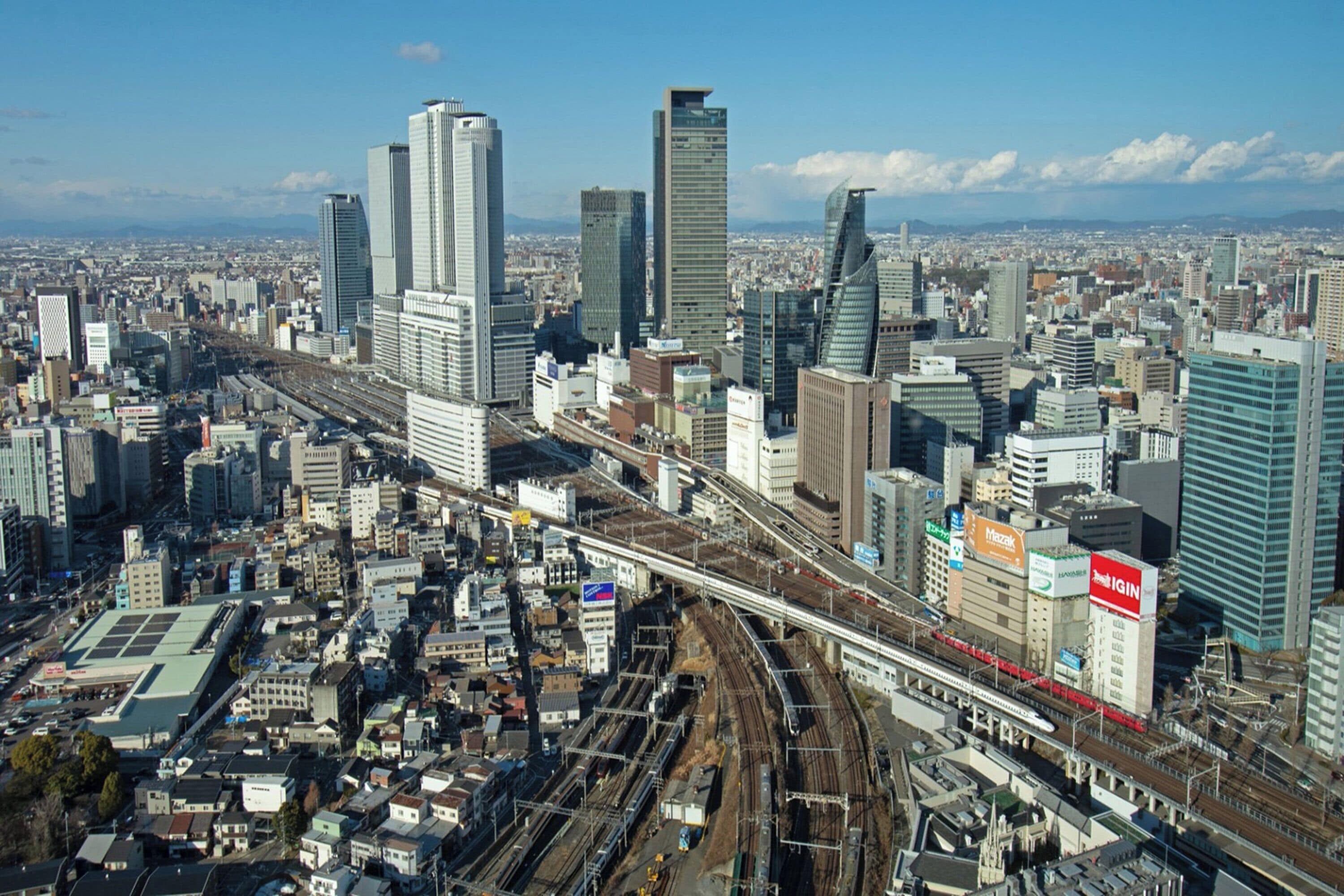 A cityscape with modern high-rise buildings, a prominent train track, and a mix of commercial and residential structures.