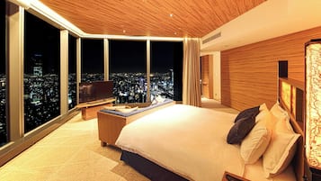 A modern hotel room with a large bed, a TV, and a city view.