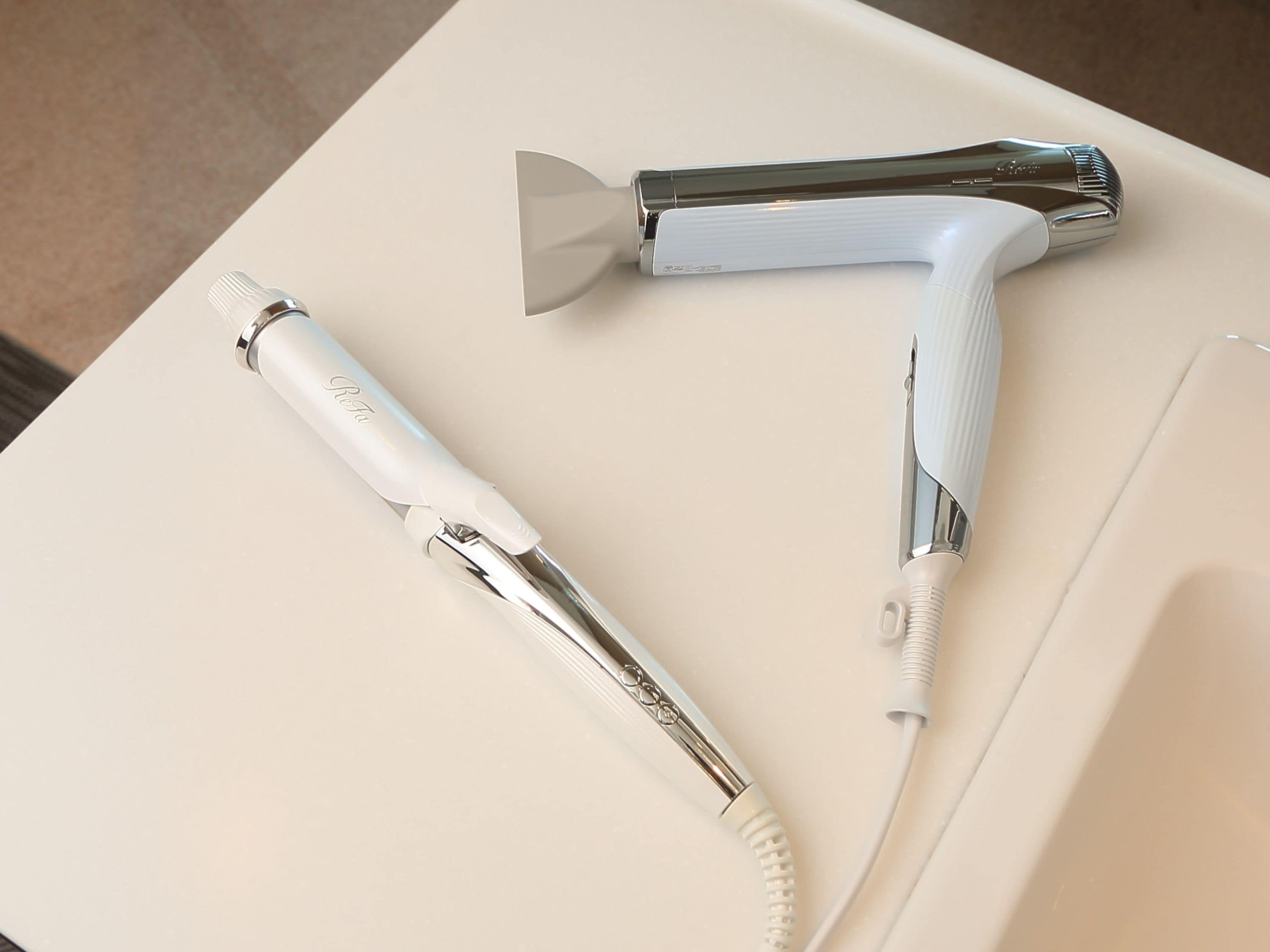 Two hairdryers on a white surface.