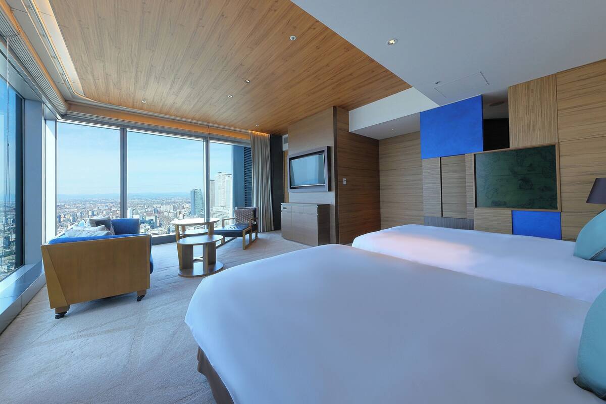 A modern hotel room with a large bed, a desk, a chair, and a TV.