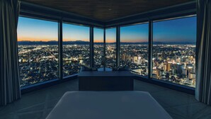 Une chambre située dans un immeuble de grande hauteur, dotée de grandes fenêtres offrant une vue sur la ville.