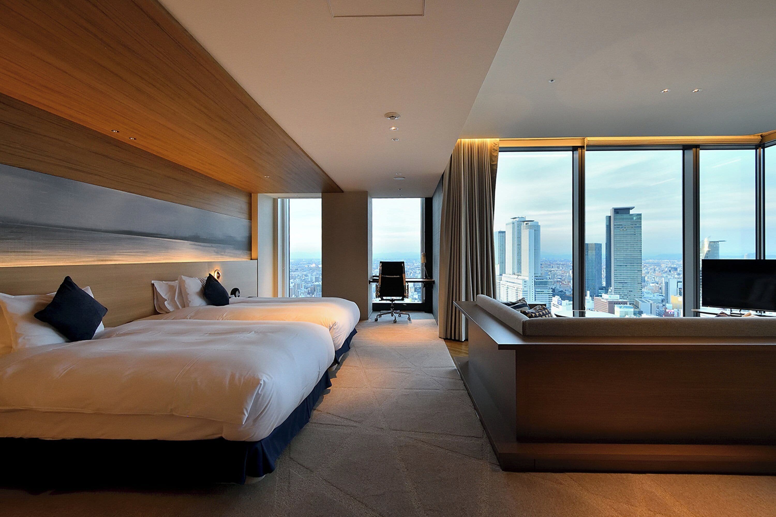 A modern hotel room with a large bed, a desk, and a TV.