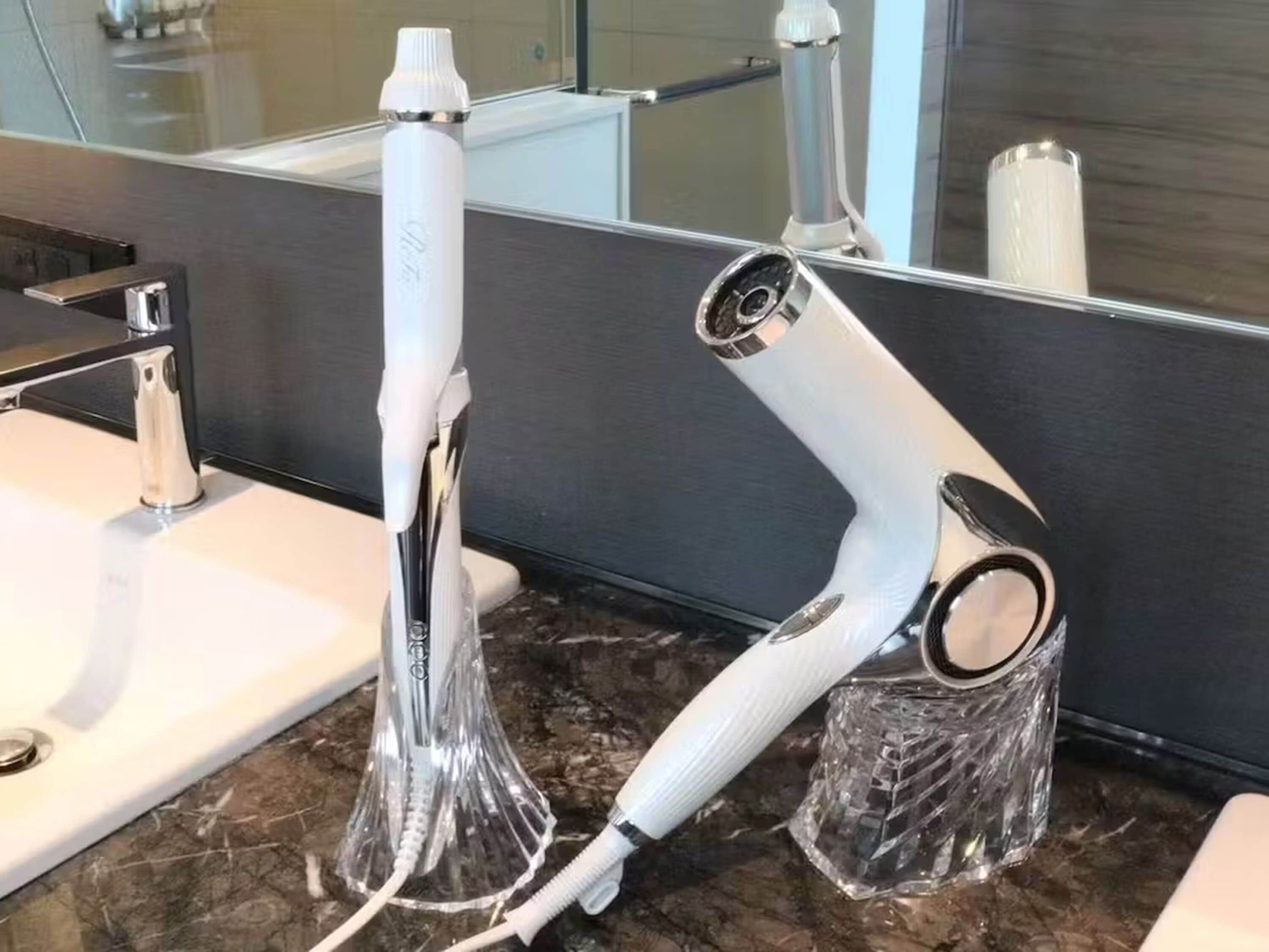 Un baño con un lavamanos moderno, un espejo y un secador de pelo sobre una encimera de mármol.