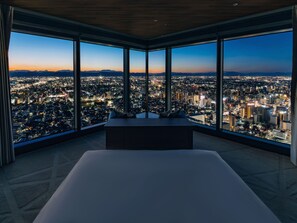A high-rise hotel room with a large bed, a view of a cityscape at dusk, and a wooden ceiling. - Nagoya Prince Hotel Sky Tower (Nagoya)