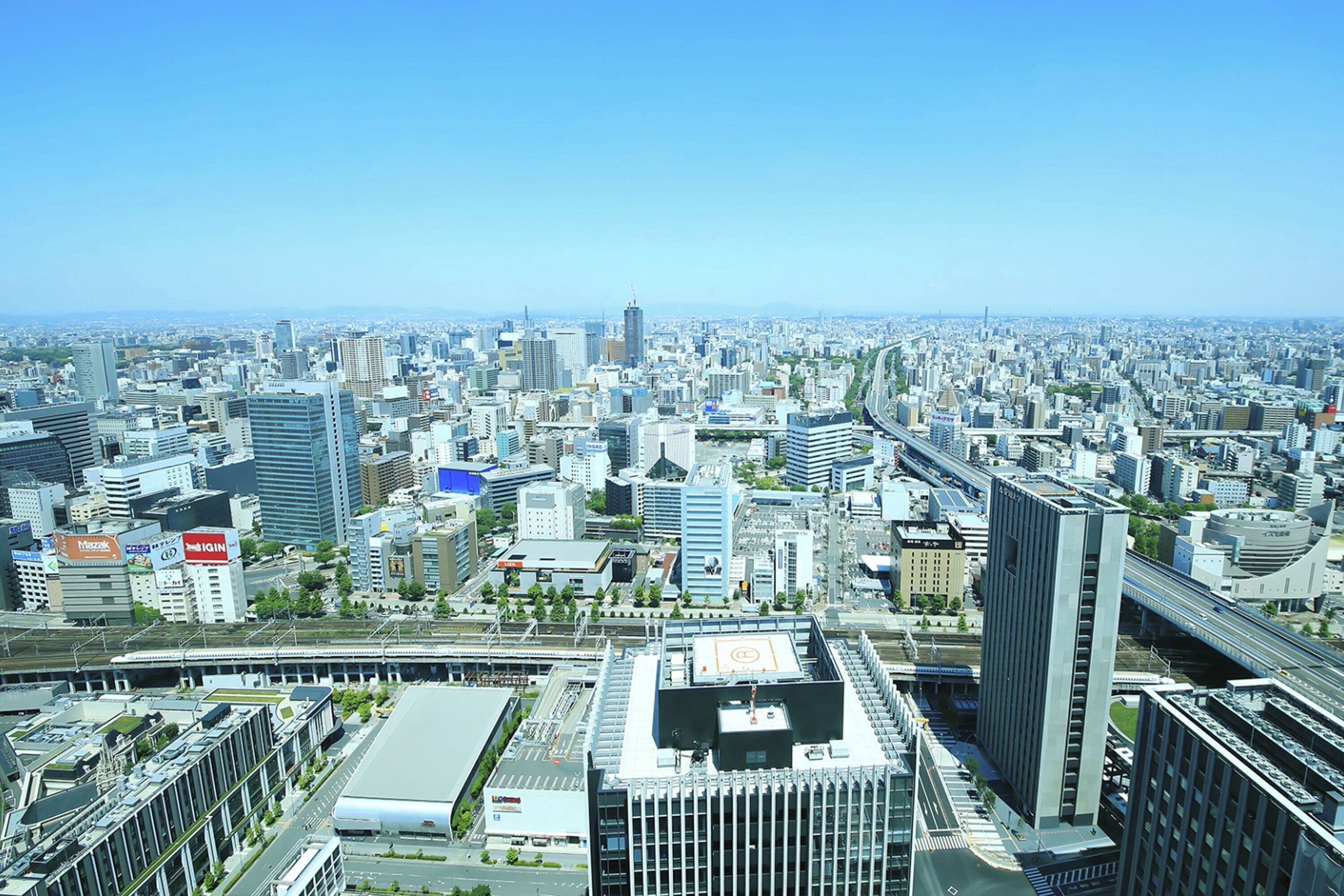 A cityscape with modern buildings, a prominent skyscraper, and a highway.