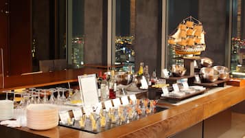A bar area with a city view, a ship model, and various food and drink items.