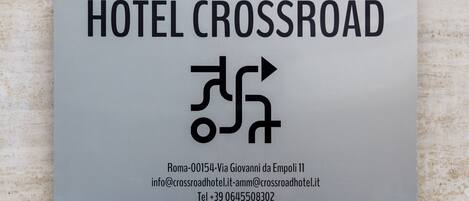 A sign for HOTEL CROSSROAD with directional arrows and contact information.