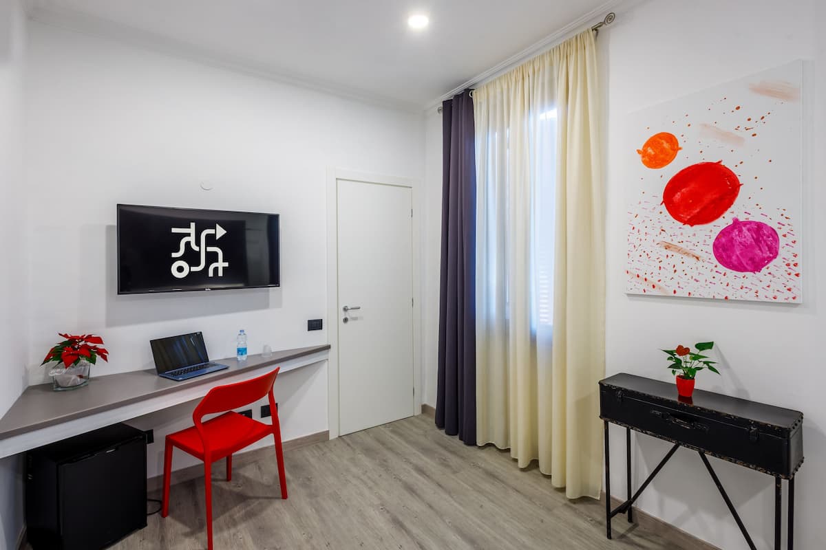 A modern hotel room with a desk, chair, and a television.