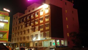 Un hotel de varios pisos con un letrero muy iluminado, múltiples ventanas y una entrada visible.
