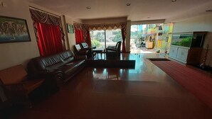 Una sala de estar con un sofá, sillas, una mesa y un televisor.