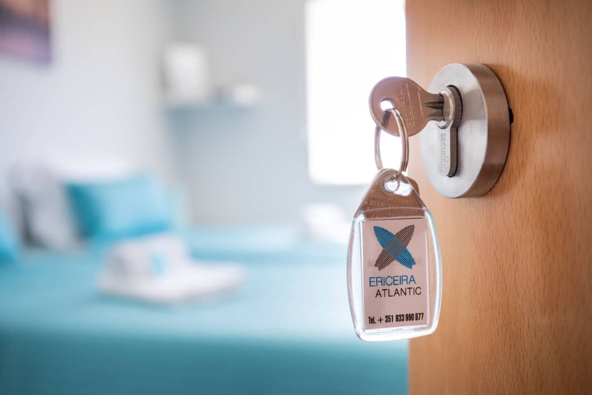 A keychain with "ERICIRA ATLANTIC" and a phone number, hanging on a door lock.
