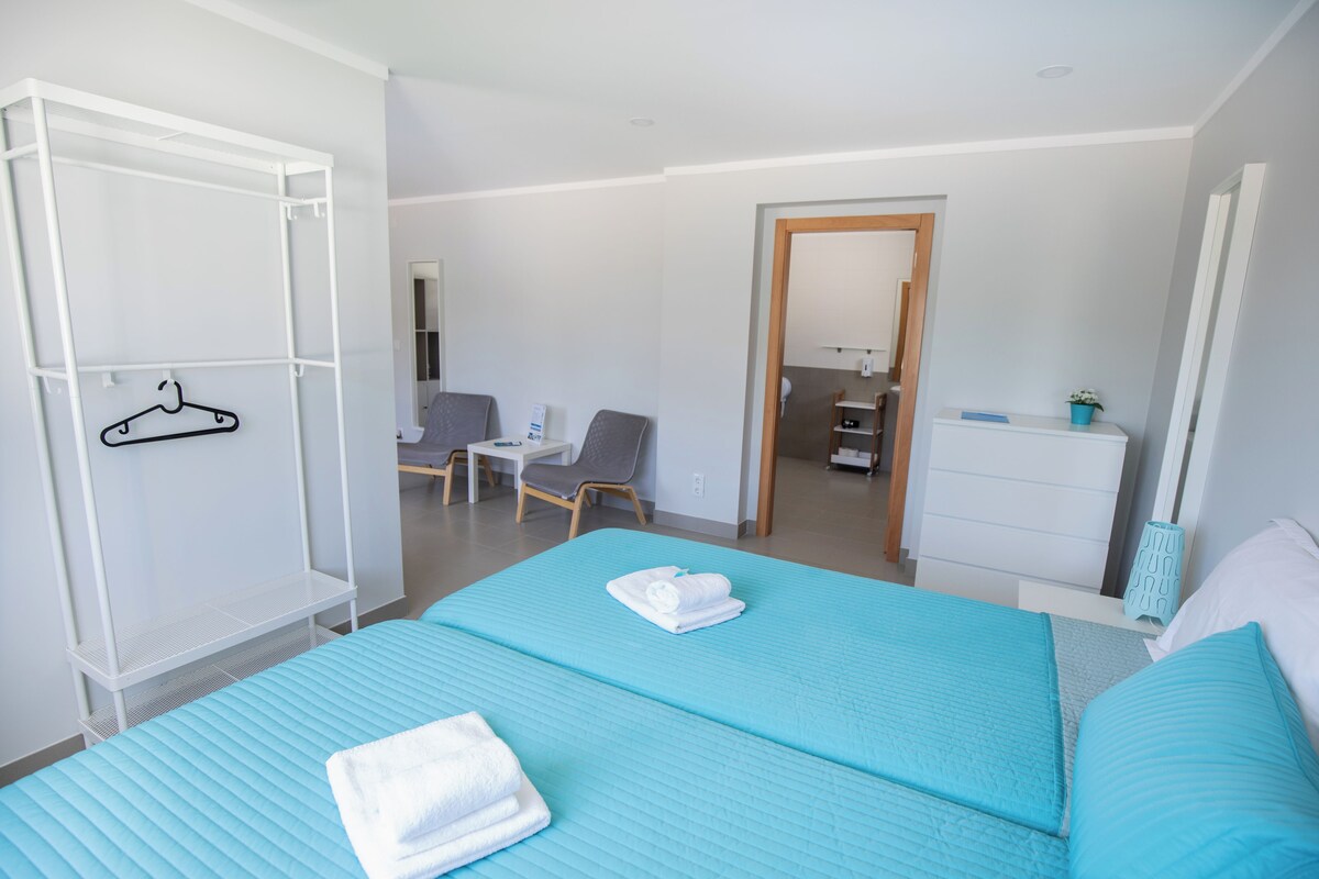 A hotel room with a bed, a desk, a chair, and a wardrobe.