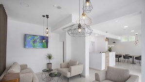 Una sala de estar moderna con sofás, una mesa de centro e iluminación colgante. Hay un cuadro en la pared y una planta sobre una mesita auxiliar.