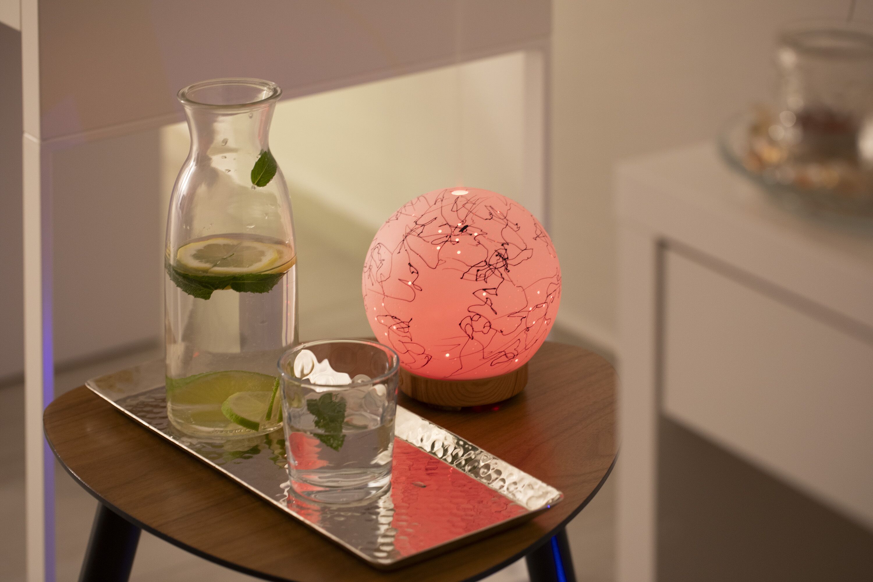 Un tavolo con una bottiglia di vetro, un bicchiere con una fetta di lime e un globo decorativo.
