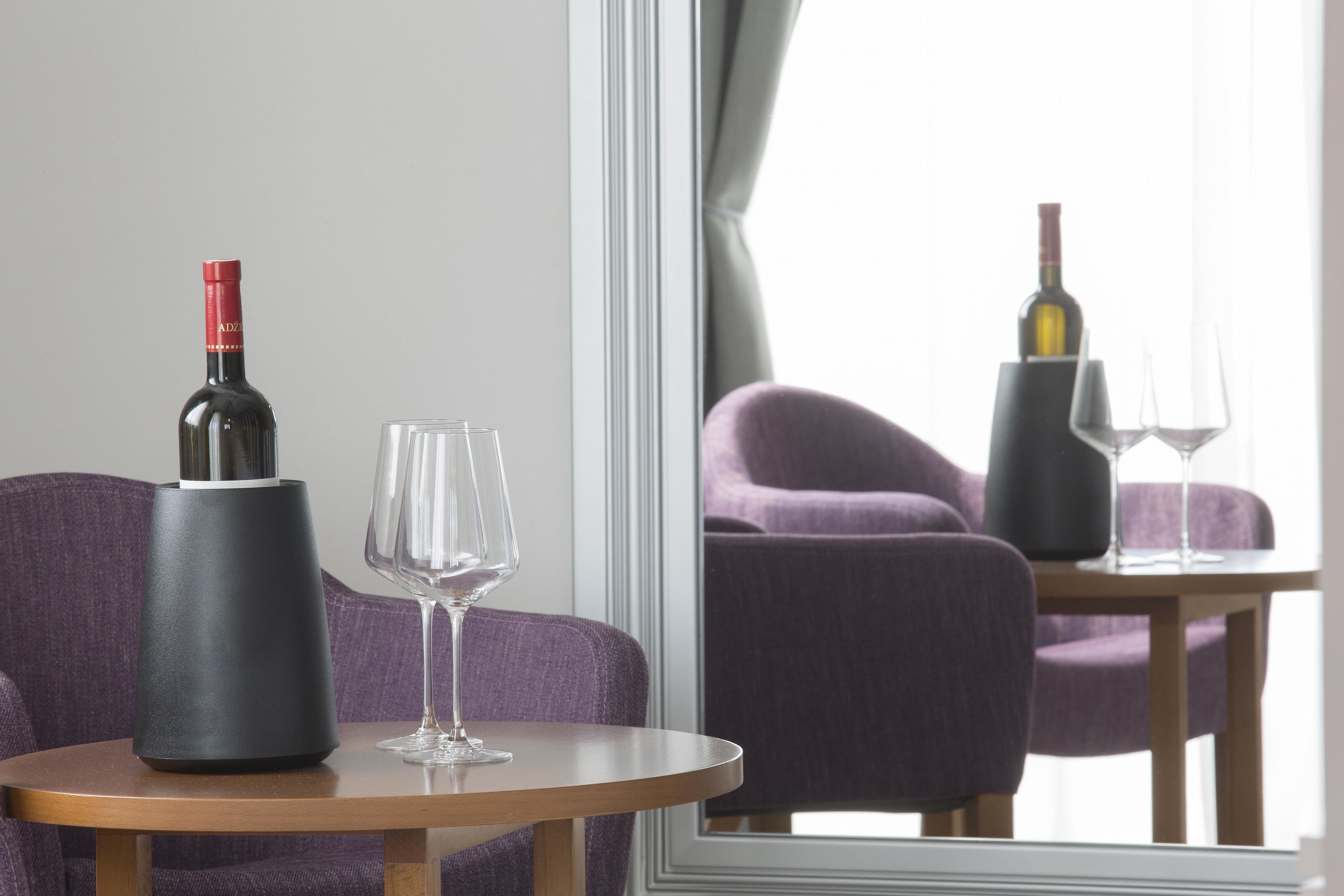 A modern room with a round table, a wine bottle, and two glasses.