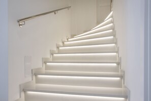 Un escalier dont les marches sont éclairées et qui est doté d’une main courante.