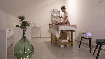Experience a serene space for relaxation, featuring a massage table, a soothing plant, and calming ambiance.