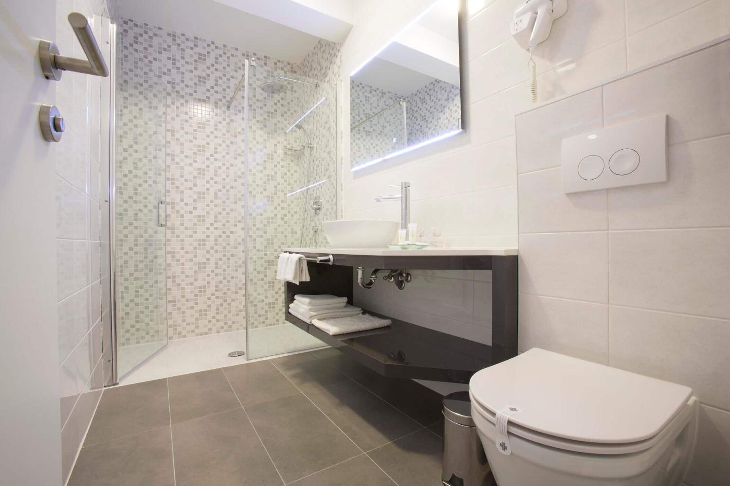 A modern bathroom with a glass-enclosed shower, a white sink, and a toilet.