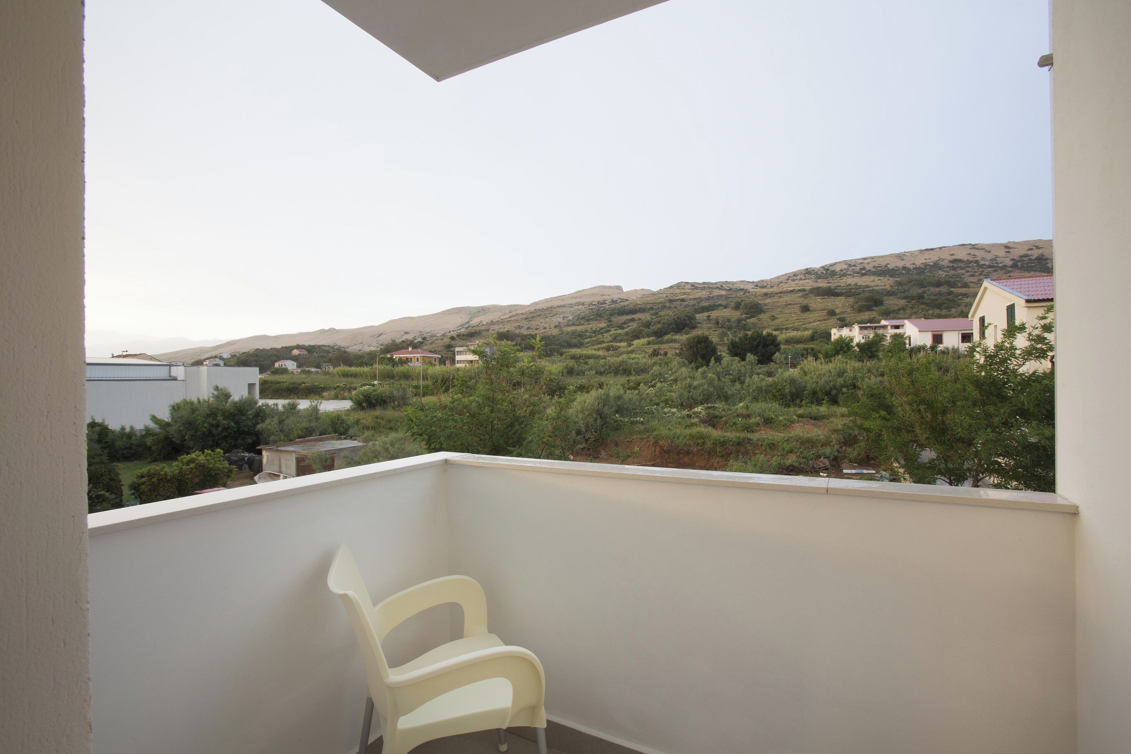 A balcony with a view of a hilly landscape and houses.