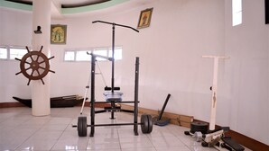 Een sportschool met trainingsapparatuur, een stuurrad en een groot raam.
