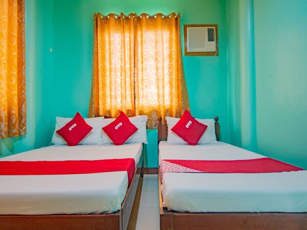 A hotel room with two beds, each with red and white bedding, and a window with a curtain.