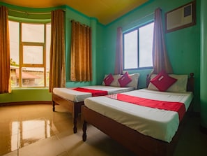 A hotel room with two beds, a window with curtains, and a tiled floor.