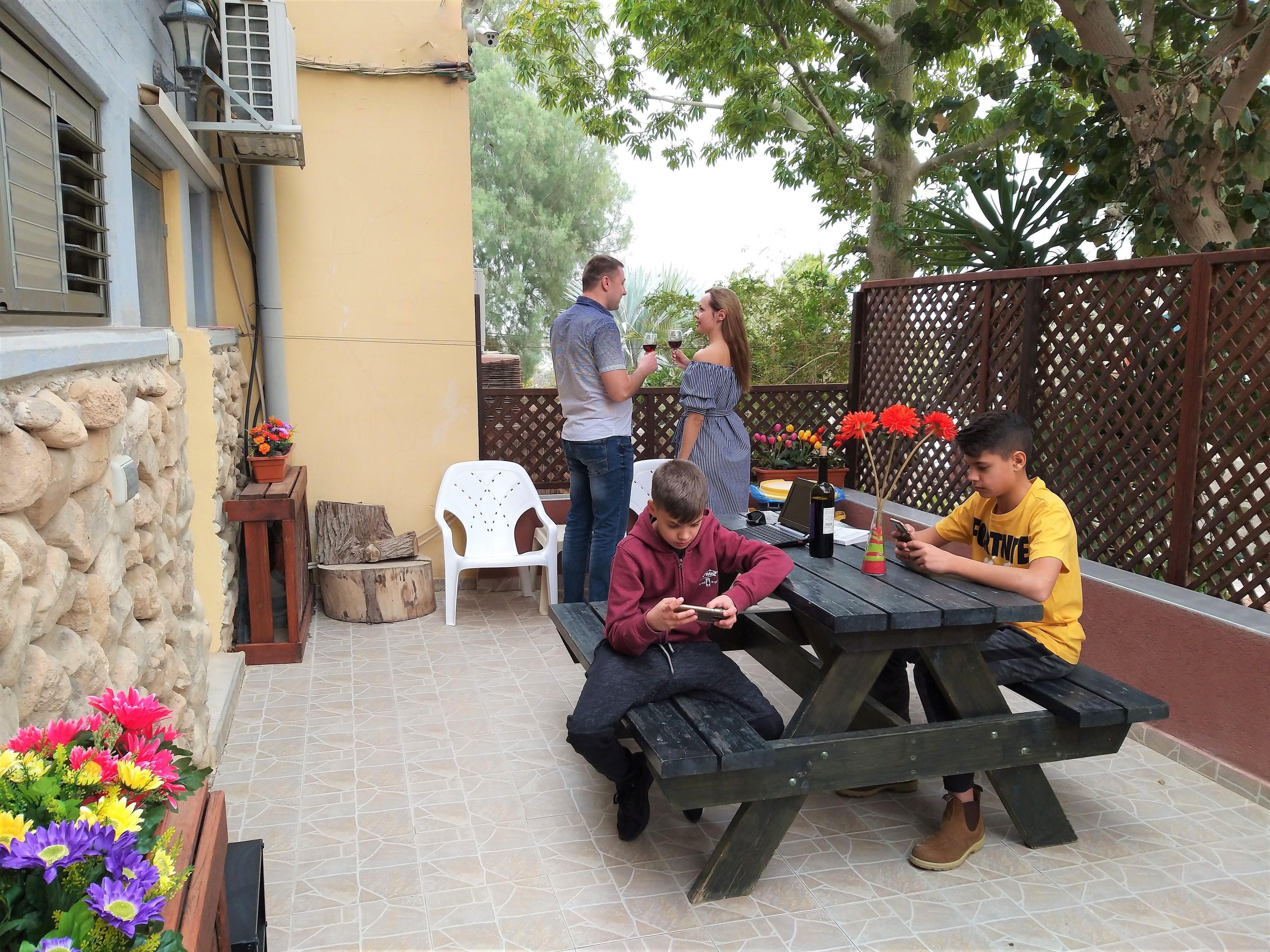 Un patio al aire libre con pared de piedra, una mesa de madera y un banco.