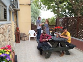 Un patio al aire libre con pared de piedra, una mesa de madera y un banco.