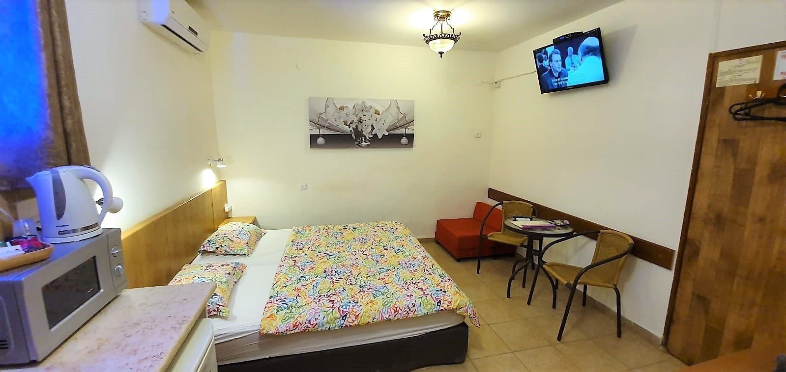 A small hotel room with a bed, a desk, a chair, a television, and a microwave.