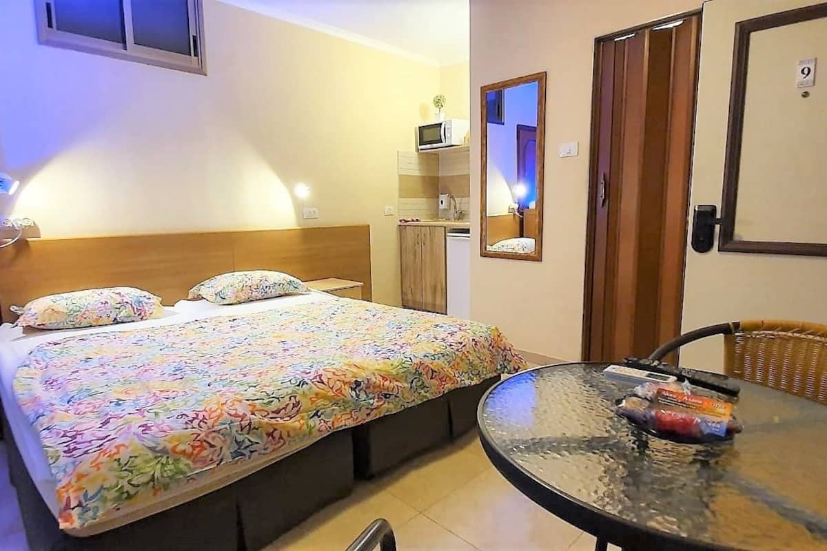 A hotel room with a bed, a small table, a chair, a microwave, and a mirror.