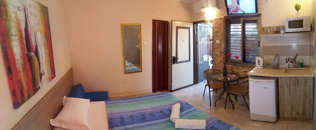 A compact room with a bed, a small dining table, a microwave, and a sink.