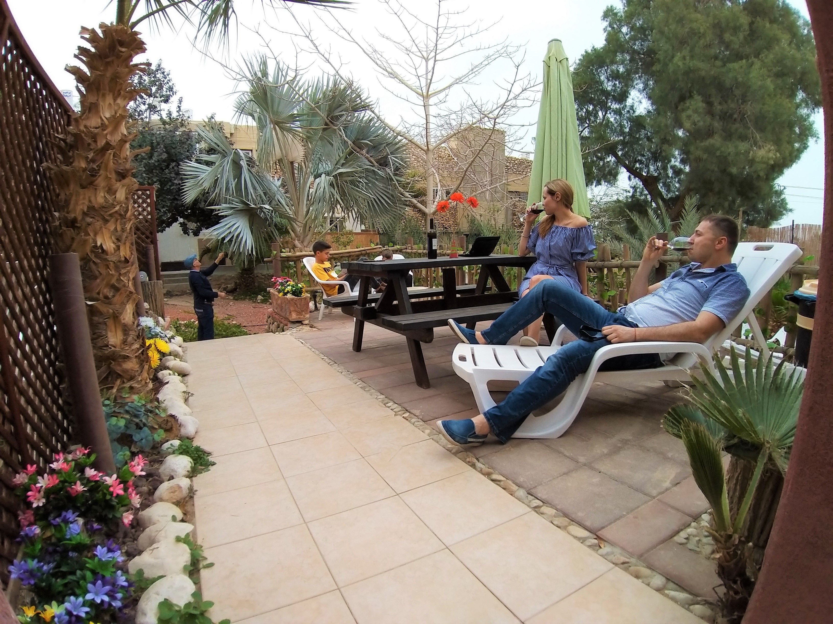 Un patio con suelo de baldosas, mobiliario exterior y diversas plantas.