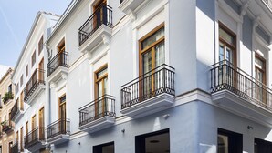 A multi-story building with balconies, large windows, and a classic architectural style. - One Shot Mercat (Valencia)