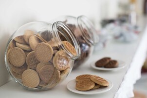 Due barattoli di vetro pieni di biscotti su un tavolo bianco.