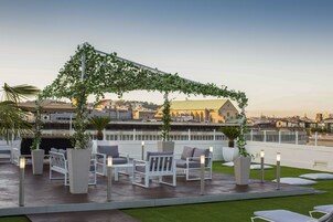Una terrazza panoramica sul tetto con posti a sedere all'aperto, una pergola e vista sulla città.