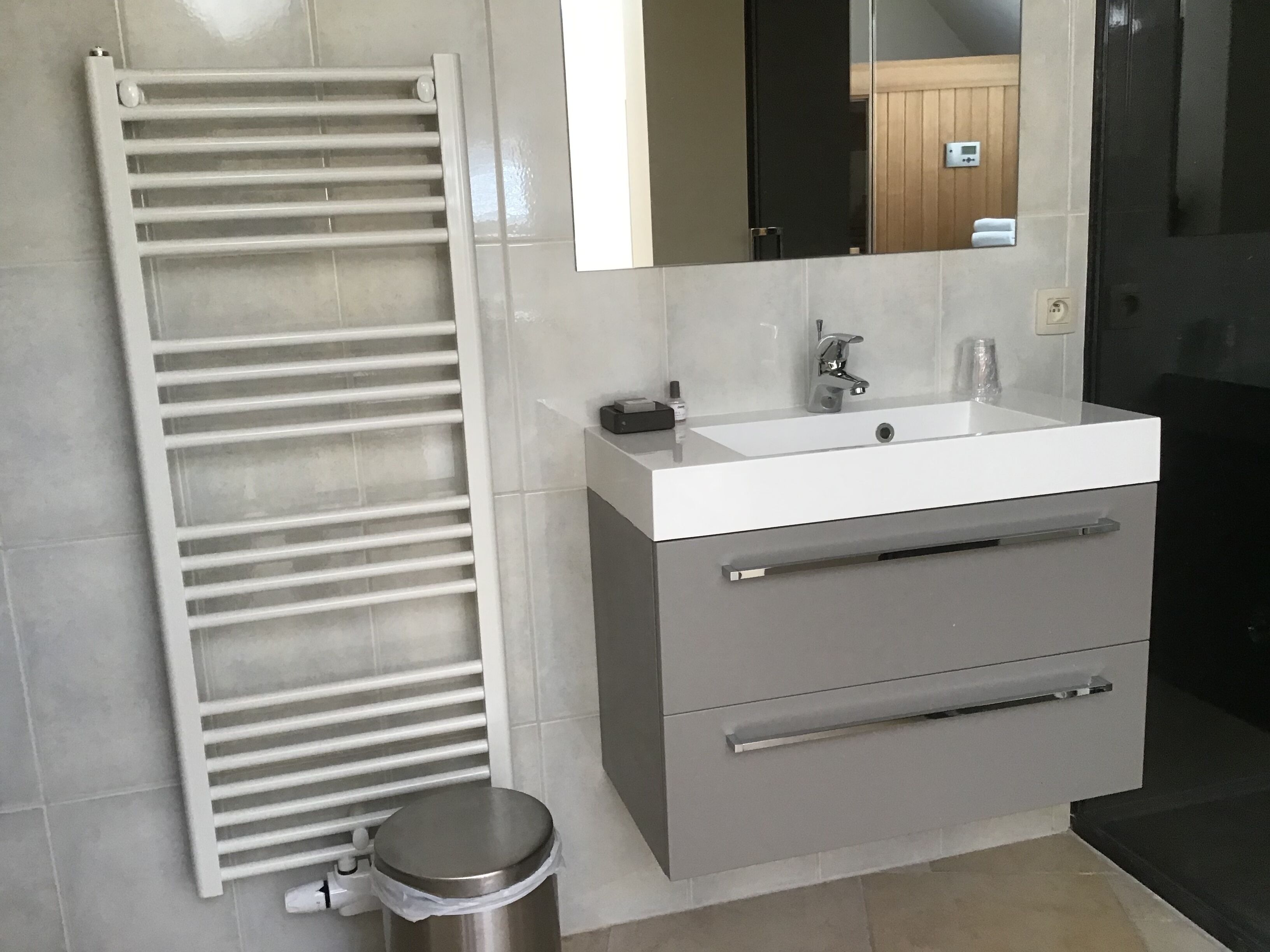 Un baño moderno con un lavabo blanco, un espejo y un perchero para toallas.