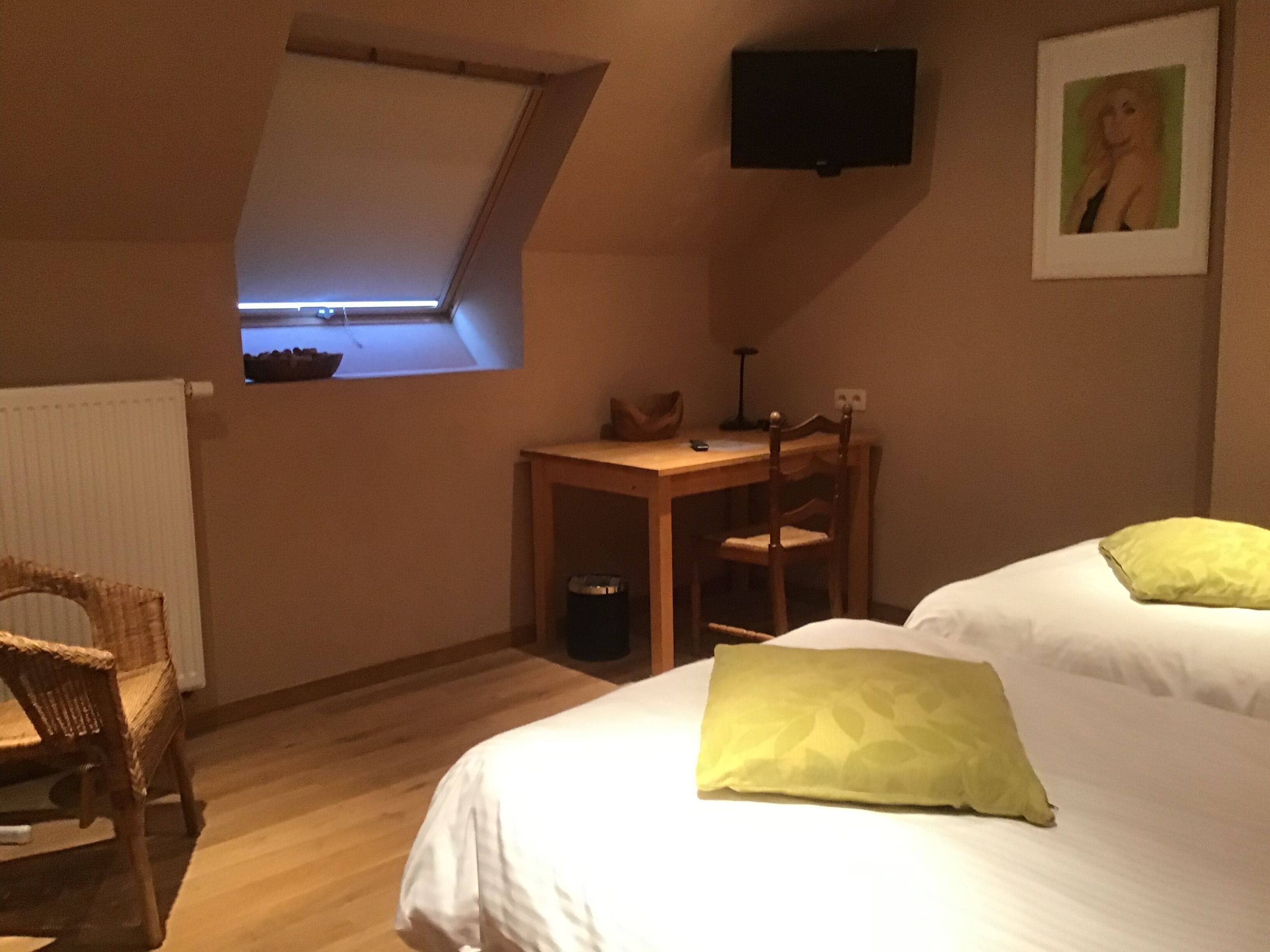 Un dormitorio con una cama, un escritorio, una silla, un televisor y una ventana.