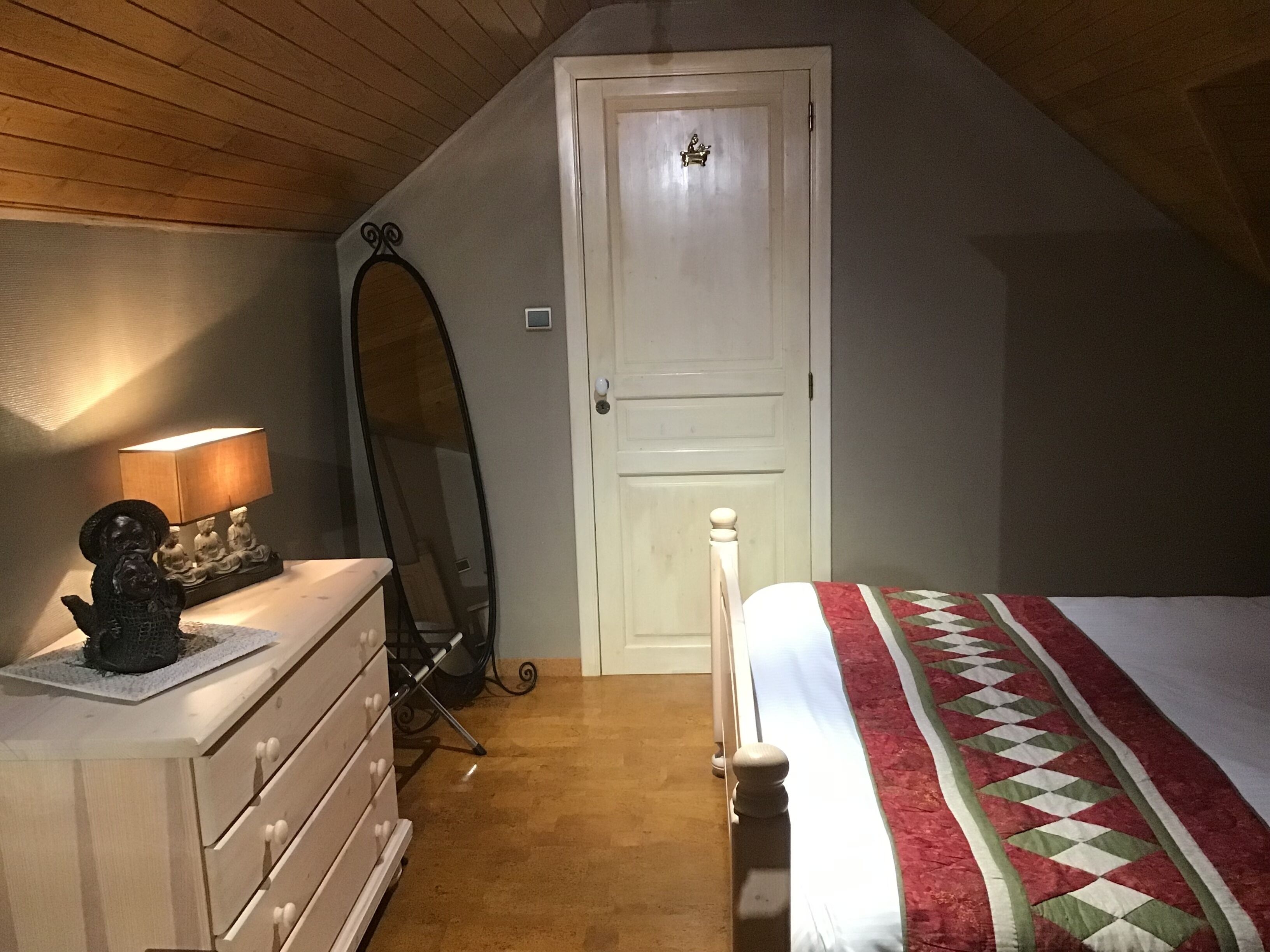 A bedroom with a bed, dresser, mirror, and a lamp.