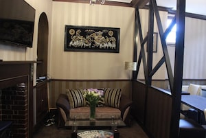 Una habitación acogedora con un sofá, una mesa de centro con revistas, un televisor y un adorno decorativo en la pared.