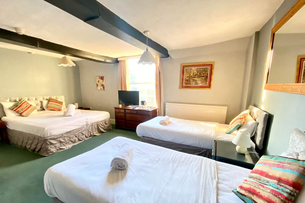 Habitación de hotel con dos camas, televisión, cómoda y ventana con cortinas.