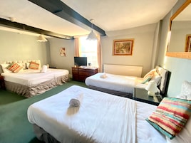 Habitación de hotel con dos camas, televisión, cómoda y ventana con cortinas.