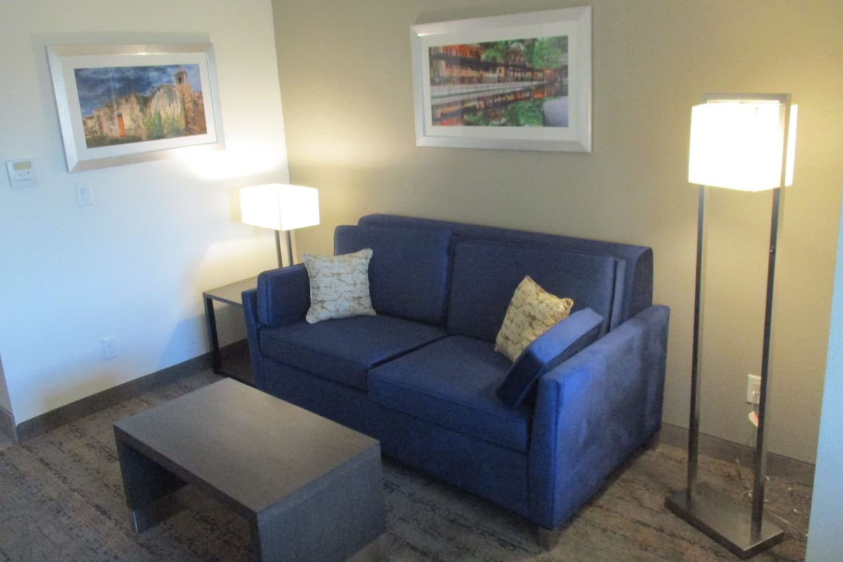 A living room with a blue sofa, two side tables, a coffee table, and two wall-mounted lamps.