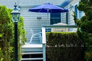 A white house with a porch, a blue umbrella, and a white chair. - Southampton Village Motel (Southampton)