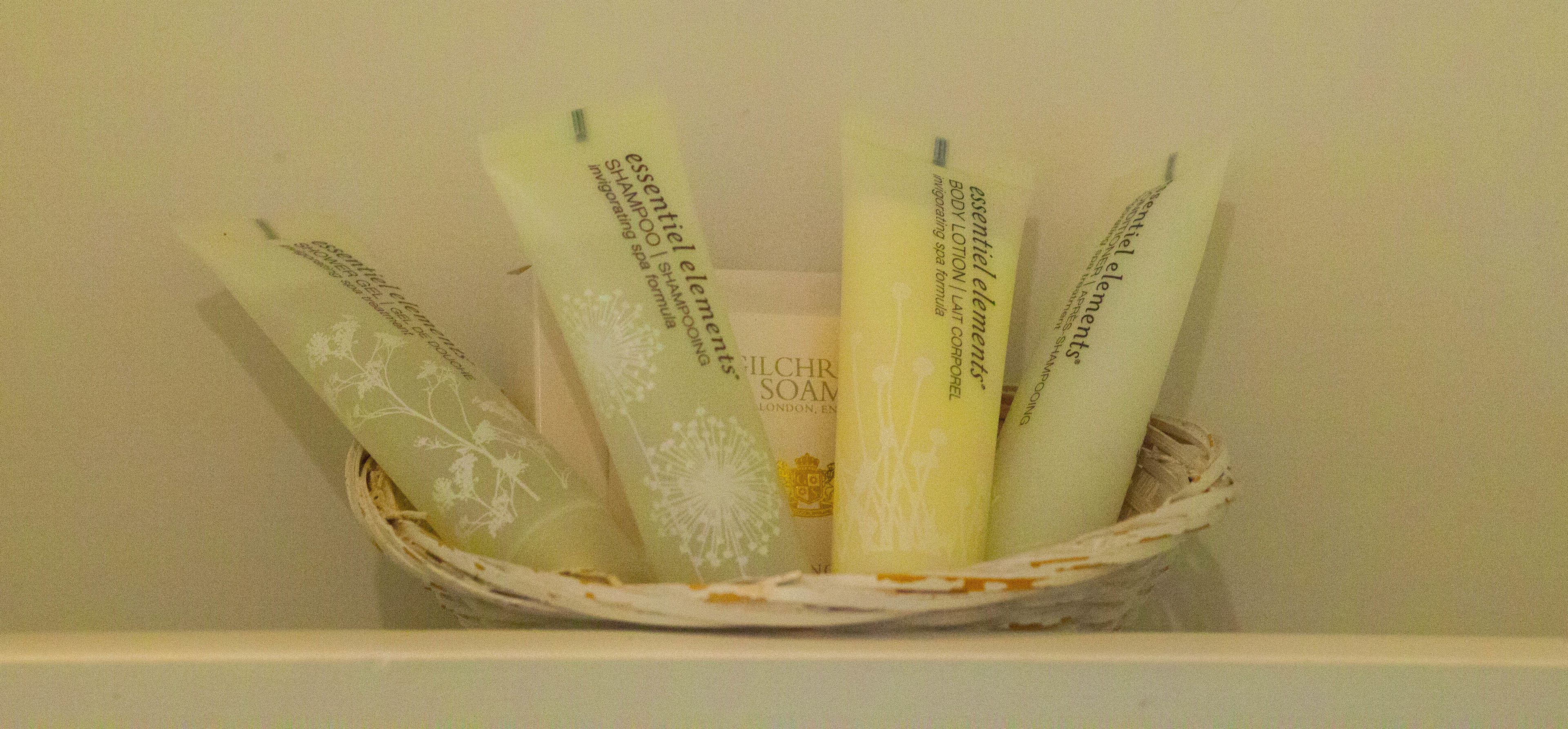 A basket containing several bottles of essential elements body lotion and shampoo.