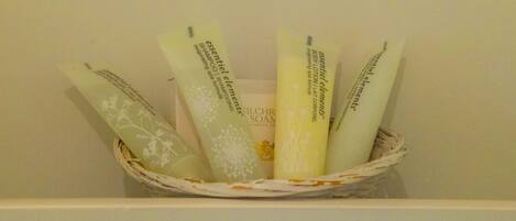 A basket containing several bottles of essential elements body lotion and shampoo.