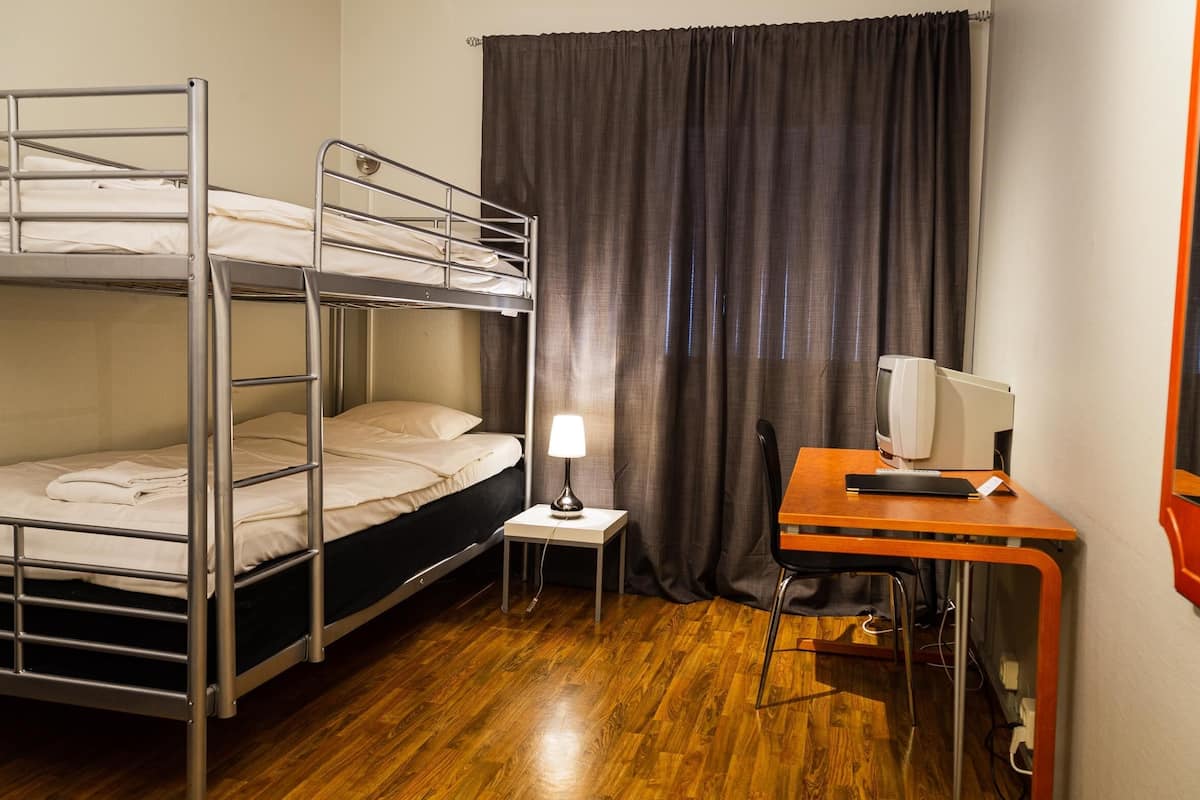 Een slaapkamer met stapelbed, bureau, lamp en televisie.