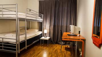 A bunk bed room with a desk, a lamp, and a television.
