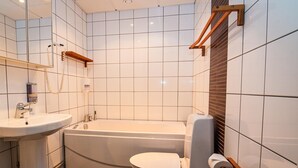 A modern bathroom with a white sink, a bathtub, and a toilet. - Skoogs BnB (Pitea)