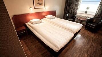 Habitación de hotel con cama doble, mesita de noche, una silla y una pequeña mesa.