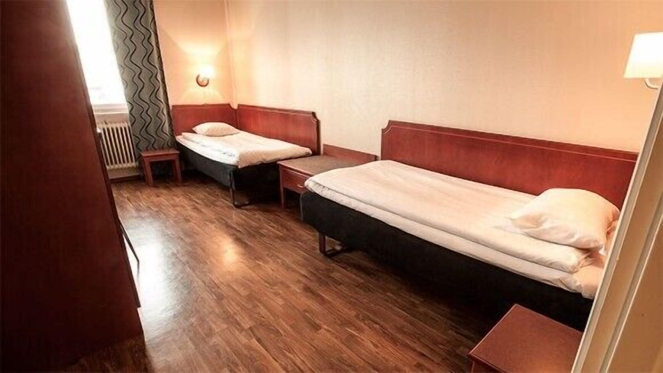 Habitación pequeña y funcional con dos camas individuales y una mesita.